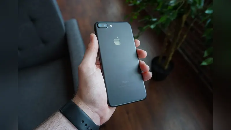 A hand holding a smartphone outdoors